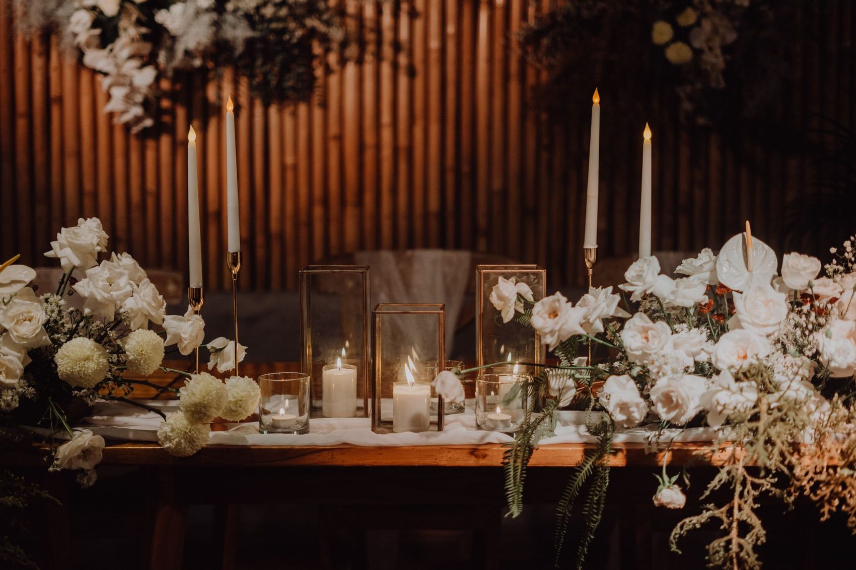 Tall candles and flowers set for an indoor ceremony
